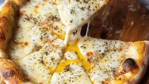 Delicious Cacio e Pepe Pizza with cheese and pepper topping served on a rustic wooden table.