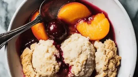 Delicious cherry and peach cornmeal cobbler served in a rustic setting