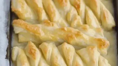 Freshly baked orange twist breadsticks with sweet glaze on a wooden table