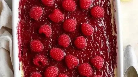 Fresh Raspberry Tiramisu dessert on a plate with raspberries and cocoa powder.