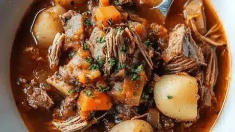 A bowl of hearty goose stew surrounded by fresh herbs and vegetables