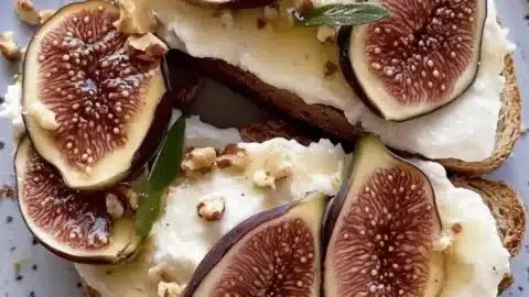 Whipped goat cheese fig toast with walnuts on a wooden board.