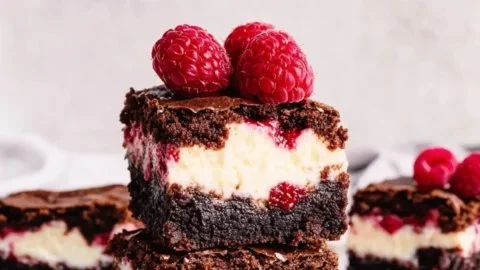 Delicious Raspberry Cheesecake Brownies with creamy topping and fresh raspberries
