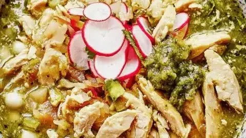 Bowl of savory Turkey Pozole Verde made from turkey leftovers garnished with green toppings.
