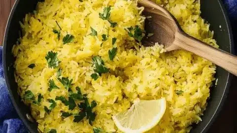 Bowl of zesty lemon rice garnished with herbs and lemon slices
