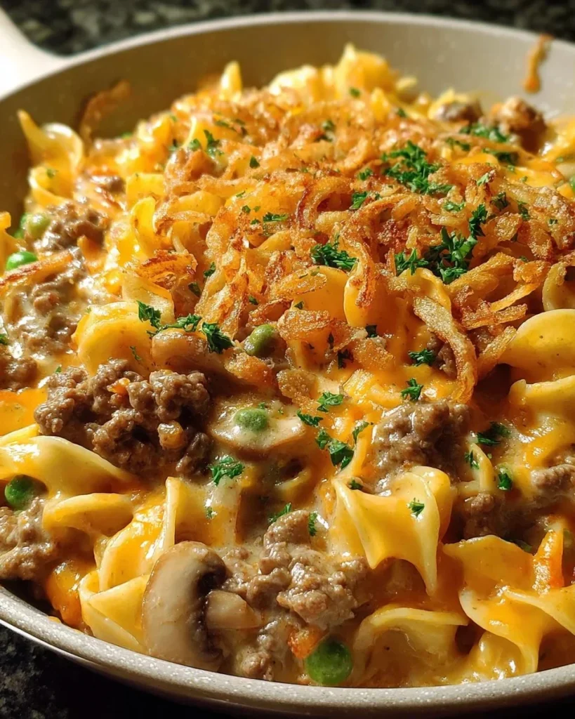 Cheesy beef noodle casserole served in a bowl, topped with melted cheese and herbs.