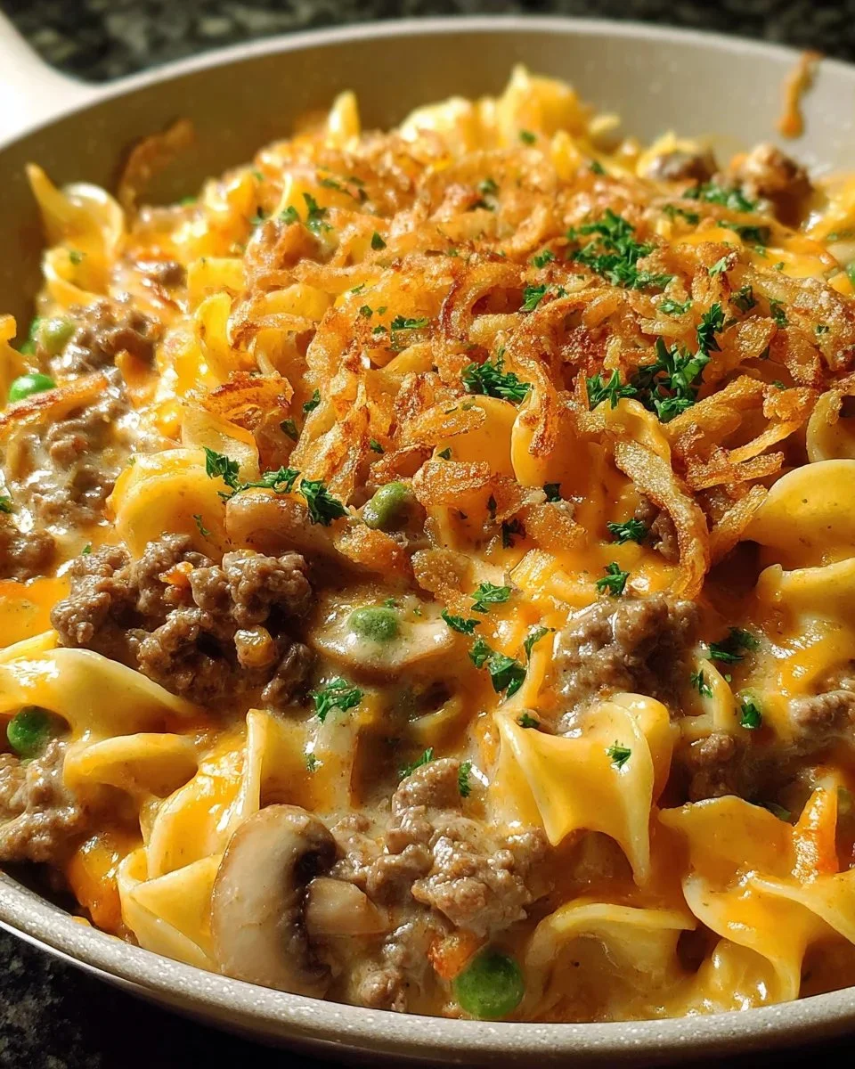 Cheesy beef noodle casserole served in a bowl, topped with melted cheese and herbs.