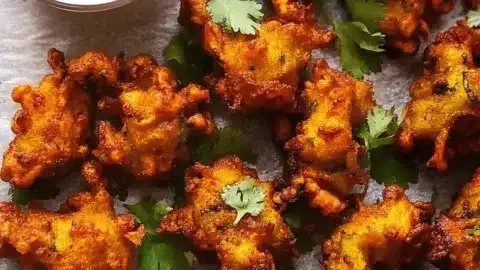 Crispy pakora served with dipping sauce, showcasing delicious Indian vegetable fritters