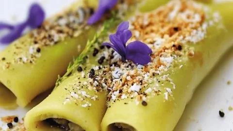Plate of delicious coconut pandan crepes topped with coconut flakes and pandan leaves