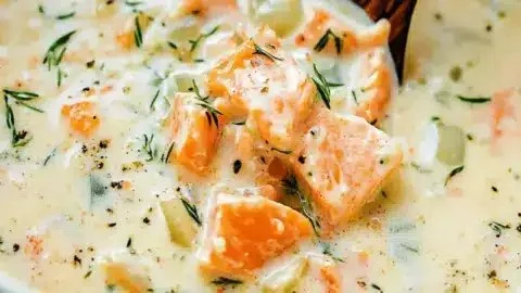 Bowl of delicious salmon chowder soup garnished with herbs and served warm