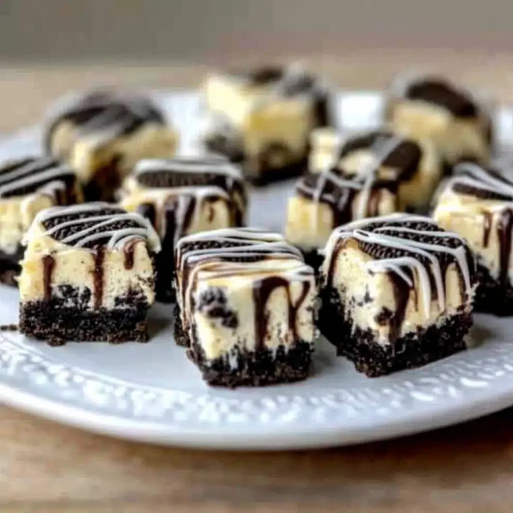 Plate of delicious Oreo Cheesecake Bites garnished with chocolate drizzle.