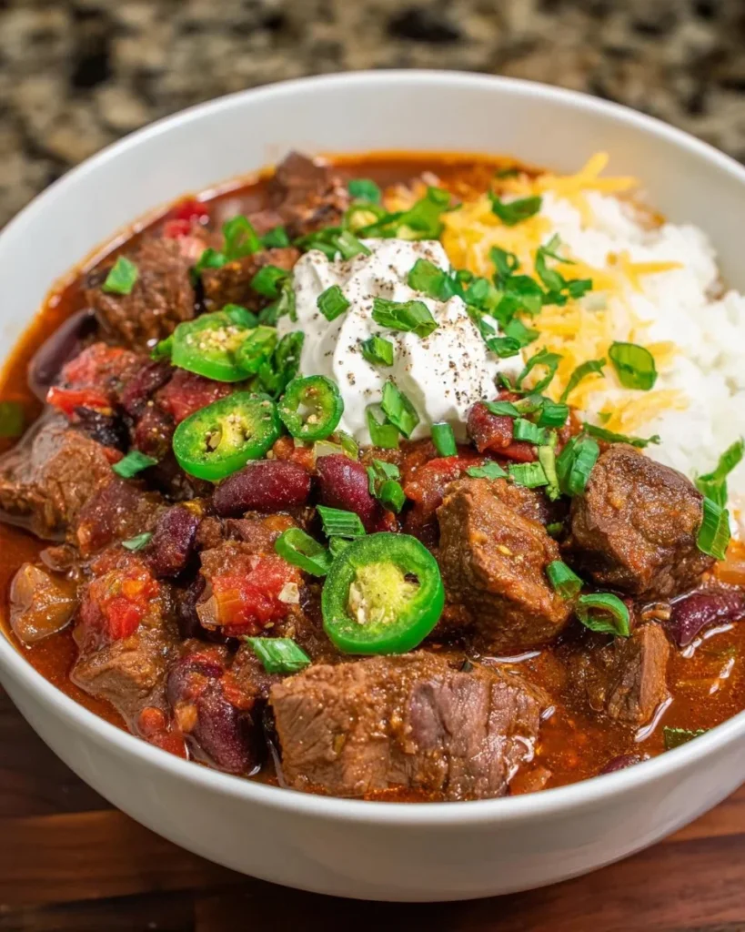 Bowl of spicy steak chili topped with fresh herbs and spices