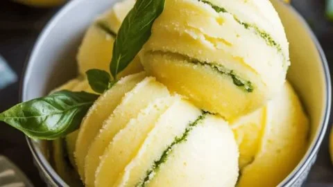 Zesty lemon basil sorbet served in a bowl with fresh basil leaves.