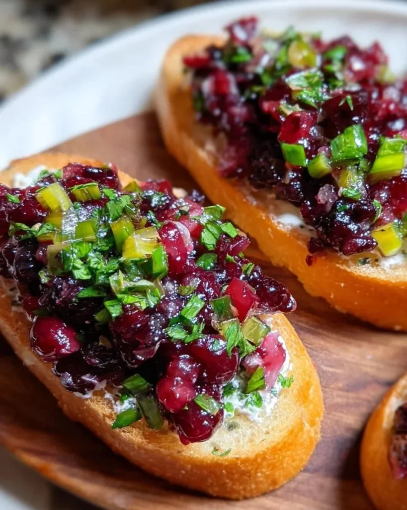 Crostini topped with Cranberry Jalapeño Tapenade, a sweet and spicy appetizer.