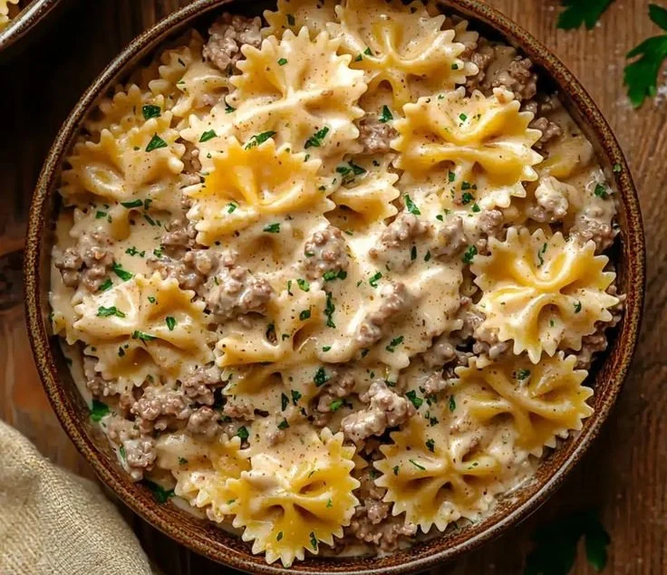 Creamy beef and bowtie pasta dish served in a bowl garnished with herbs