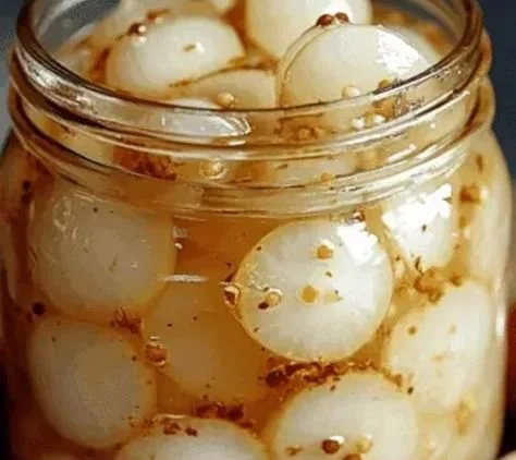 Jar of homemade pickled pearl onions in a rustic kitchen setting