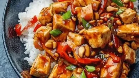 Delicious bowl of vegan Kung Pao Tofu with colorful vegetables and peanuts