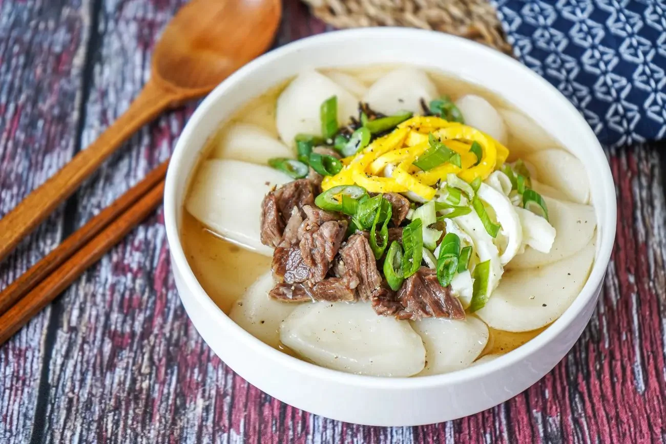 Bowl of Korean Rice Cake Soup (Tteokguk) garnished with green onions.