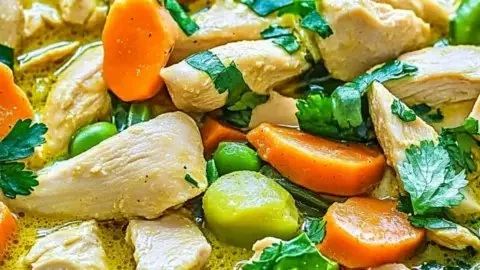 Bowl of delicious green Thai chicken coconut curry garnished with herbs