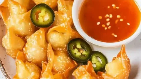 Plate of jalapeño cream cheese wontons garnished with dipping sauce