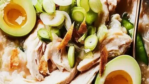 Bowl of Arroz Caldo, a chicken rice porridge garnished with green onions