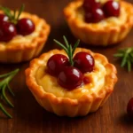 Savory chicken cranberry brie tartlets on a wooden table, ready to serve.
